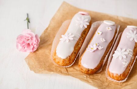 Traditional french eclairs on white table with pink flower