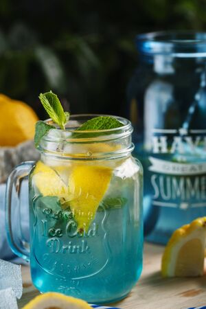 Citrus lemonade water with lemon sliced , healthy and detox water drink in summer on wooden table on a background green foliageの写真素材