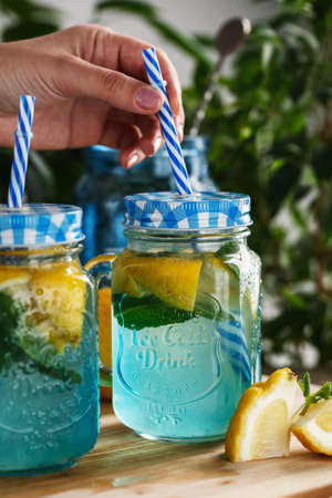 Citrus lemonade water with lemon sliced , healthy and detox water drink in summer on wooden table on a background green foliageの写真素材