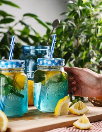 Citrus lemonade water with lemon sliced , healthy and detox water drink in summer on wooden table on a background green foliageの写真素材