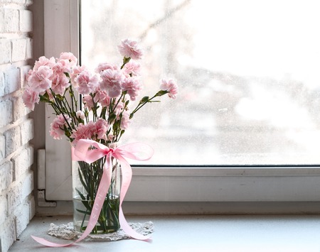 pink carnations on white windowsill. White brick wallの写真素材
