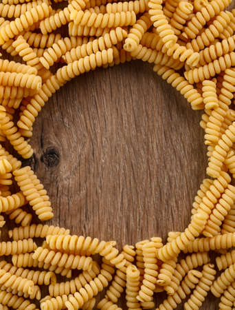 Italian raw pasta fusilli on wooden backgroundの写真素材
