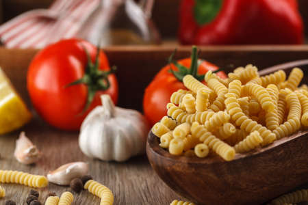 Italian raw pasta fusilli on the background of other ingredients for cookingの写真素材