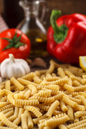 Italian raw pasta fusilli on the background of other ingredients for cookingの写真素材