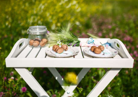 walnuts and a bouquet of wild flowers on a white table in the middle of the field
