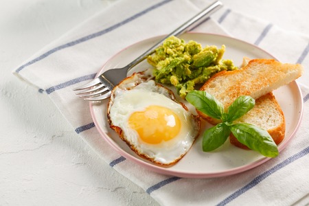 breakfast. egg, avocado and toasts with basil on white textile background. Closeup.の写真素材