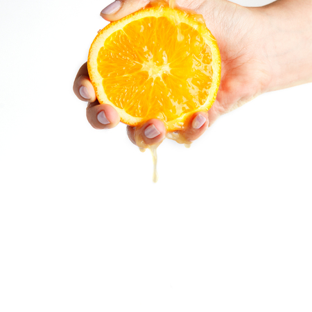 female hand crushes orange on white background