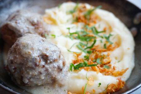 meat balls in sauce with mashed potatoes, French fries and herbs. Closeup