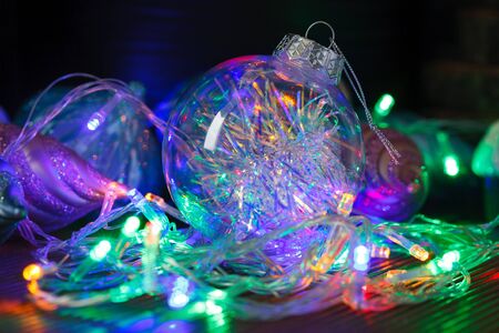 Beautiful transparent Christmas ball with lights from the garlands on dark background