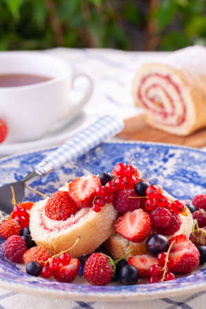 dessert with fresh berries in a blue vintage plate. Sweet roll. on white background.