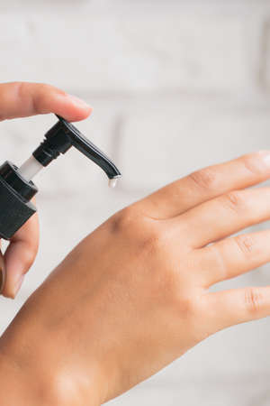 A woman pours lotion or hand cream from a bottle into her hand. The concept of skin care. Close-up of women's hands holding a bottle of creamの写真素材