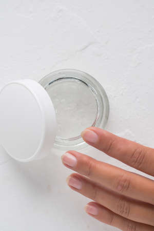 A womans hand with a jar of face cream on a white background. The concept of cosmetics.の写真素材