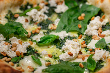 Vegetarian spinach pizza with ricotta cheese and pine nuts on a stone background. Closeupの写真素材