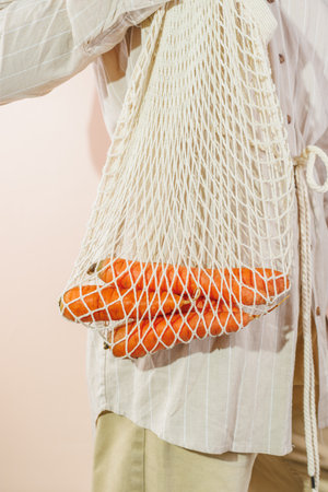 fresh carrots in a shopping bag that hangs on the girl's shoulderの写真素材
