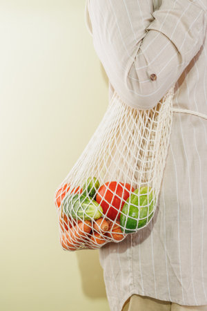 different vegetables in the shopping bag that hangs on the girl's shoulder. Copy spaceの写真素材