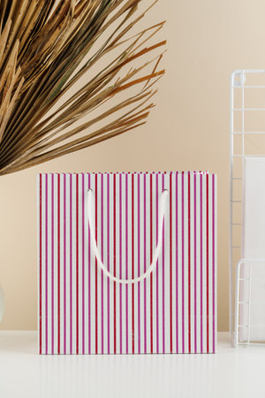 a gift paper bio-package with purple stripes on a beige background and dried palm leaves. Mockupの写真素材