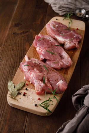 a piece of fresh raw pork meat with spices on a brown wooden table. Meat with spices. Top viewの写真素材