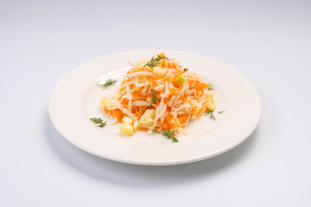 Dinner. Cabbage and apple salad with carrots on a white plate and a white backgroundの写真素材