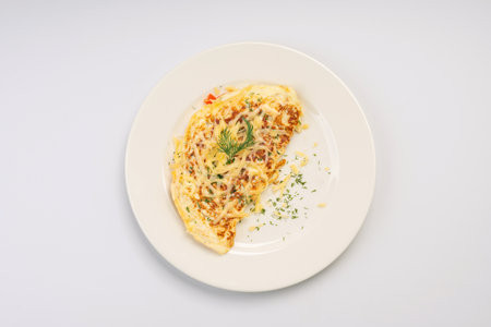 Breakfast. Omelet with vegetables and cheese on a white plate and a white background.の写真素材