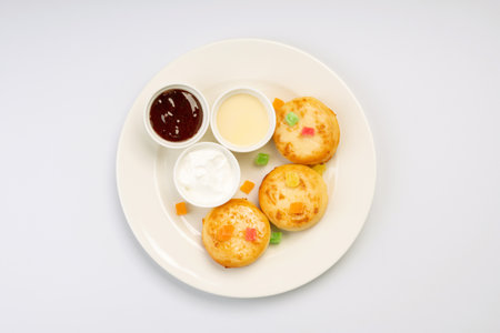 Breakfast. Cheesecakes with sauces and dried fruits on a white plate and a white background.の写真素材