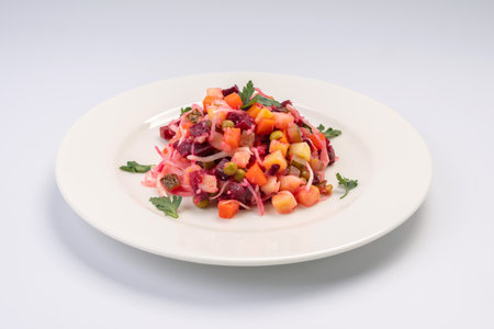 Dinner. Traditional Russian vegetable salad Vinaigrette on a white plate and a white backgrounの写真素材