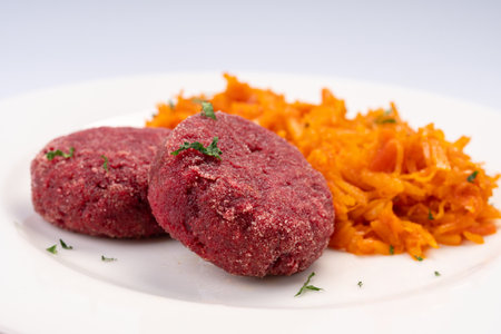 Business lunch. Vegetarian. Beetroot cutlets with stewed cabbage on a white plate and a white background.の写真素材