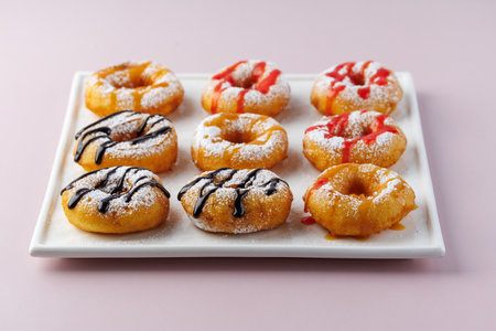 donuts with powdered sugar and various toppings on a white plate on a pale purple background. Top view. Copy spaceの写真素材