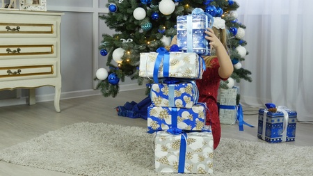 beautiful girl looking for gifts under the Christmas treeの写真素材