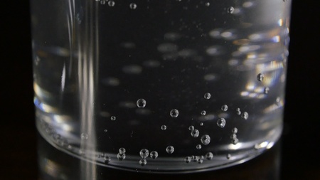 Just a glass of water on a dark wooden table. Mineral water in a glass on a black background. A glass with water.の写真素材