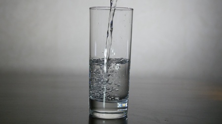 Pouring water from filter pitcher in glass on white backgroundの写真素材