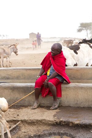 masai shepherd sitting near a fountain in tanzaniaのeditorial素材