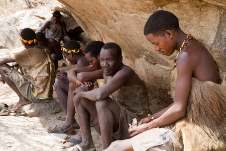 hadzabe tribe, men sitting in the shade of a rock