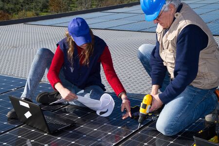 young engineer girl and an elderly skilled worker fitting a photovoltaic plant