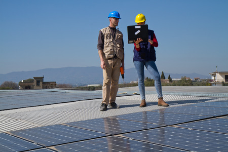 young engineer girl and an elderly skilled worker fitting a photovoltaic plantの写真素材