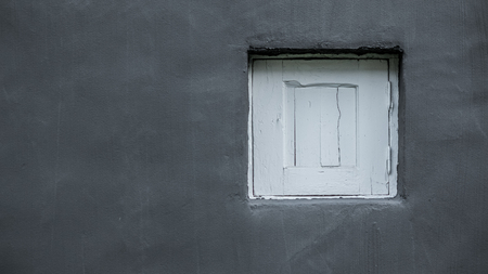 Little old aged white wooden window hatch on gray solid ruff cement concrete texture wall