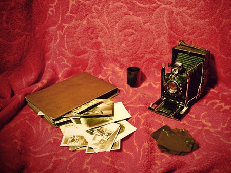 A very old camera (from the beginning of the XXth century) set with an old album , old photographs and some film over a retro background. Effects made like it it was a really old photographyの写真素材