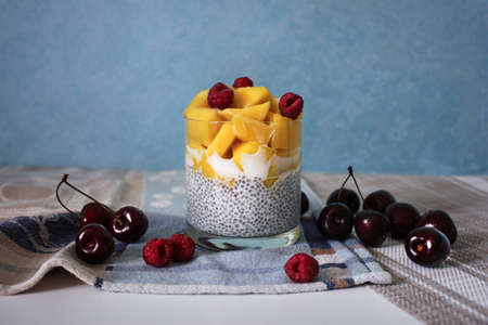 Chia pudding made of mango, coconut milk, Chia seeds, decorated with raspberriesの写真素材