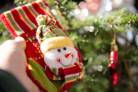 Boot for gifts with a snowman in a child's hand on the background of a Christmas tree.の写真素材