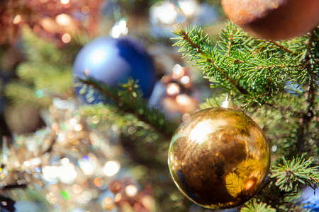 Christmas background with gold and blue Christmas tree toys on the Christmas tree on a blurry shiny backgroundの写真素材