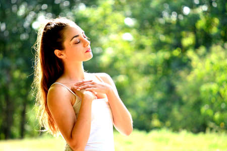 pretty young brunette woman feeling well-being in sunny parkの写真素材