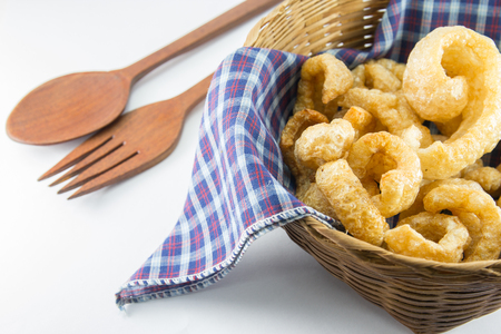 Pork snack, Pork rind, Pork scratching or pork crackling in basket with wood spoon and fork on wihte backgroundの写真素材