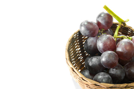 red grape in bamboo basket on white backgroundの写真素材