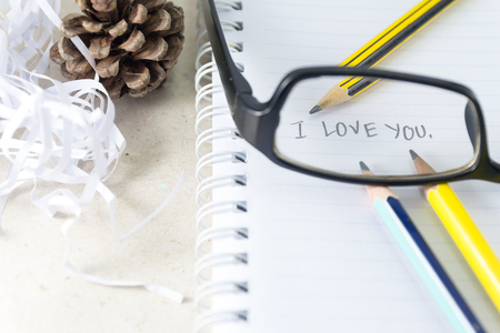 Word "I Love You" on notebook with pencil and eye glassesの写真素材