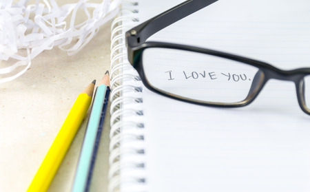 Word "I Love You" on notebook with pencil and eye glassesの写真素材