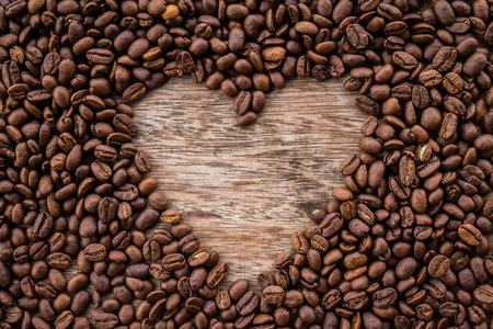 Coffee beans arranged as a heart shape on old wooden backgroundの写真素材
