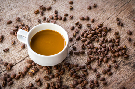 Cup of coffee on a wooden desk with coffee beansの写真素材