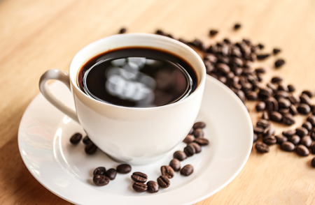 Coffee cup and coffee beans on wooden table with vintage filterの写真素材