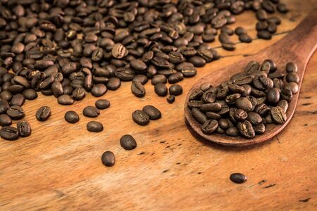 Full of coffee bean in wooden spoon on wood backgroundの写真素材