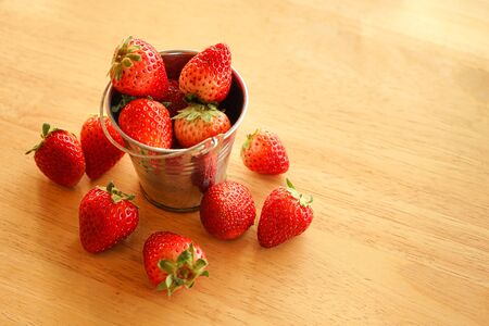 fresh strawberry in  small stainless steel water bucket on wooden desk with copy spaceの写真素材