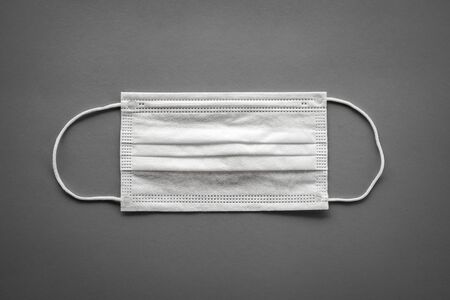 White surgical mask with rubber ear straps on grey backgroundの写真素材